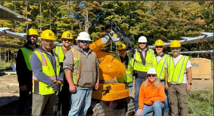 The Nexamp pilot crew in hard hats gathered around a LUMI on site