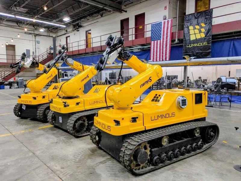 A row of LUMIs on the manufacturing floor, with the Luminous banner behind them